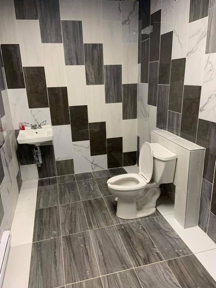 Tiled bathroom with a newly installed toilet and wall-mounted sink