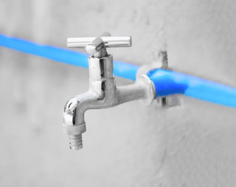 Chrome wall tap connected to a blue water pipe
