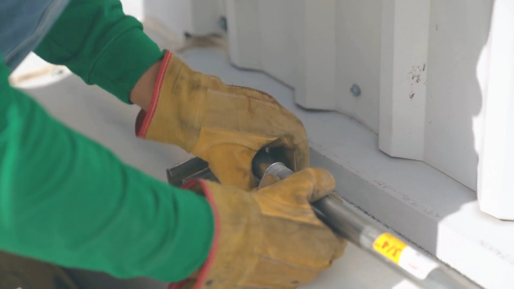Gloved hands tightening a fitting on a pipe